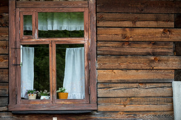 Traditional vintage old brown wooden frame window with curtains and flowers on wooden wall