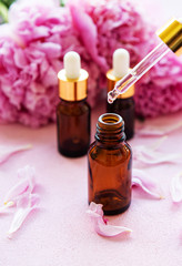 Fototapeta na wymiar Aromatherapy essentials oils and pink peonies
