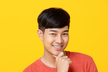Handsome young Asian man smiling with hand on chin