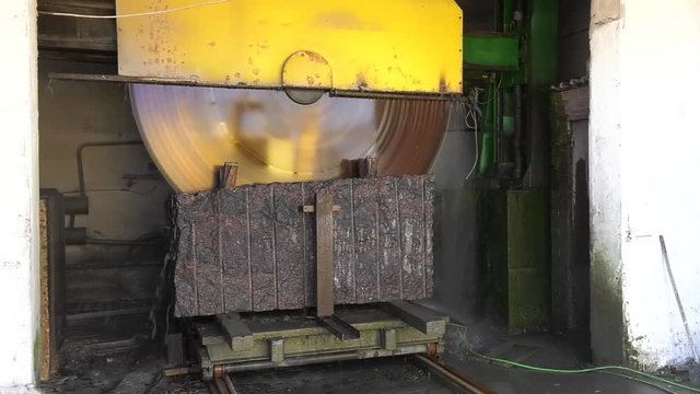 Granite processing in manufacturing. Cutting granite slab with a circular saw.  Wet granite saw, cutting moment, Industrial marble cutting factory, Granite cooled with water while being cut. 
