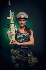 Fototapeta premium the girl in military special clothes posing with a gun in his hands on a dark background in the haze