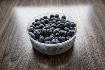 Fototapeta na wymiar Ripe tasty blueberries and berries on a wooden table in a bowl