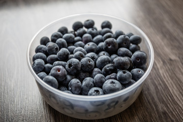 Ripe tasty blueberries and berries on a wooden table in a bowl