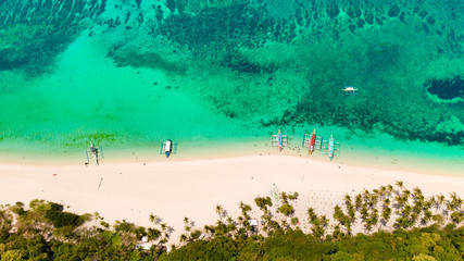 Turquoise lagoon with a coral reef and white beach. Beach with white sand and palm trees, view from above. Puka Shell Beach, Boracay Island, Philippines, aerial view.