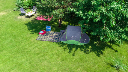 Aerial top view of campsite from above, tent and camping equipment under tree, family vacation in camp outdoors concept 