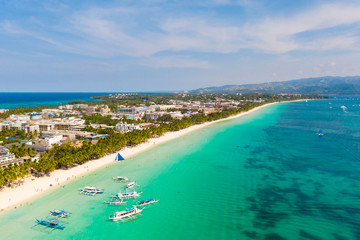 Island Boracay, Philippines, view from above. White beach with palm trees and turquoise lagoon with boats. Buildings and hotels on the big island.