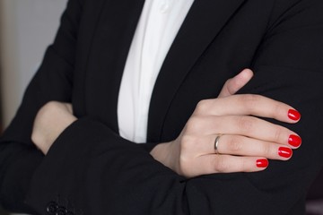 young woman with red nail polish wearing a white shirt and black suit crossing her hands