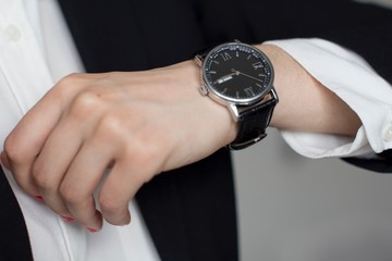 young woman in a white shirt and black suit wearing men's wristwatch