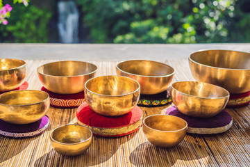 Tibetan singing bowls on a straw mat against a waterfall
