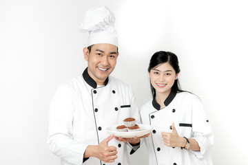 Thumb up pastry chefs holding cupcakes on white plate and checking up before serve.
