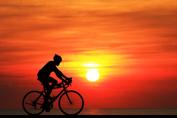 Fototapeta na wymiar Silhouette man and bike relaxing on blurry sunrise sky background.