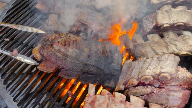 Barbecue assorted delicious fatty organic marinated meat on the bone of beef, mutton pork, cooked on a rotary grill over charcoal 4k Slow motion.