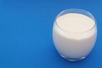 Glass of milk on blue background with room for text