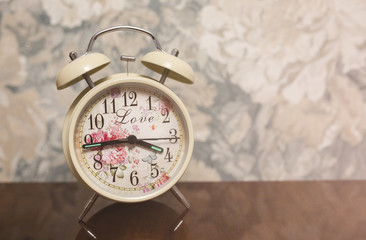 Beautiful alarm clock standing on wooden table. Good idea for present. Romantic decoration for flat.