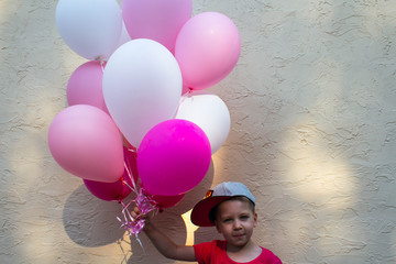 a handsome boy holds in his hand many colored balloons