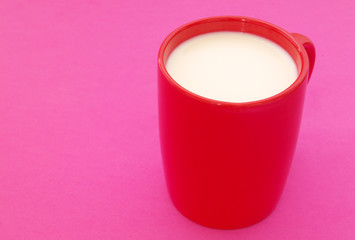 Red cup of milk on pink background with space for text