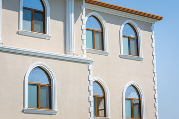 Fototapeta na wymiar Neat building with semicircular windows against blue sky.