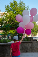 a boy holds in his hand a lot of colored balloons