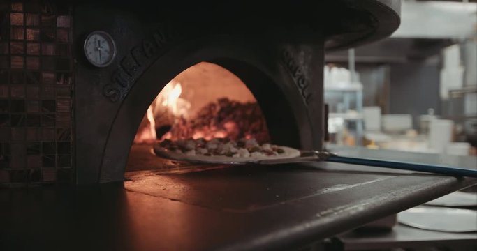 Neapolitan pizza being placed into a brick oven open flame. Authentic Neapolitan Pizza cooked in a wood fire oven.