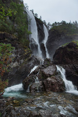 Travel to Norway, a high waterfall falls into the river and flows down from the rocks.