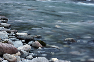 Travel to Norway, stones and pebbles on the bank of a rapidly flowing clear river