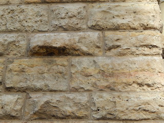 Stone wall in ocher color close up, facing building, beautiful background
