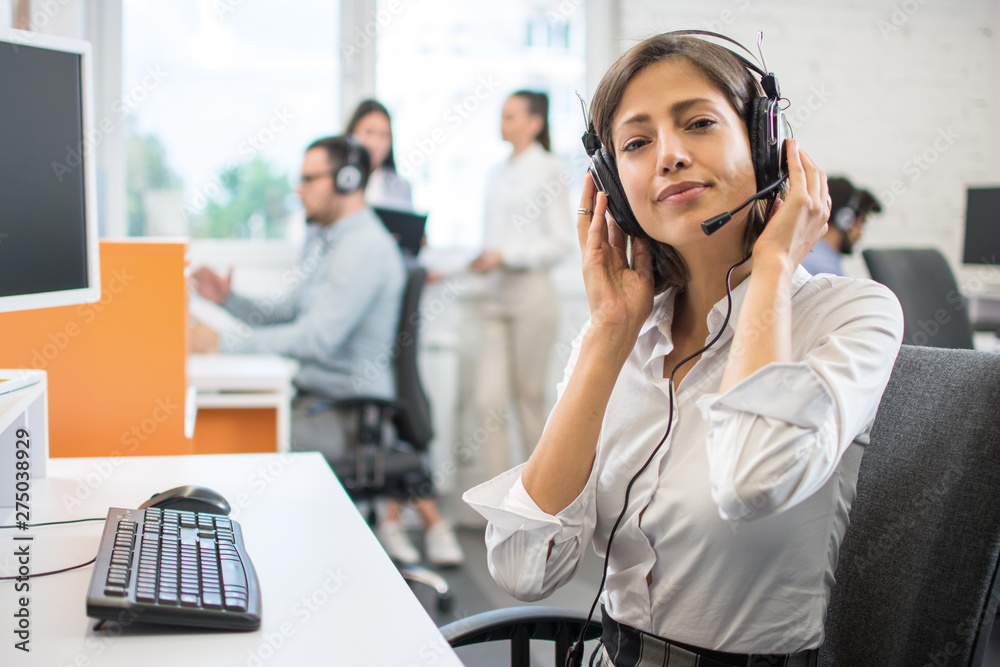 Wall mural Young friendly operator woman agent with headsets working in a call centre.