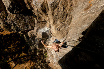 Climber Extreme climbs a rock on a rope with the top insurance, top view from above
