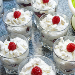 Making fresh cream dessert in glasses with fresh raspberries