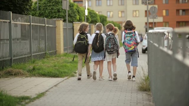 schoolchildren, a boys and a girls, go to school with backpacks. Back view. Back to school, knowledge day