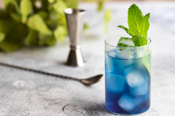 Blue lagoon, Tropical cocktail served with ice cubes decorated with mint. Refreshing alcohol drink for party at summer.