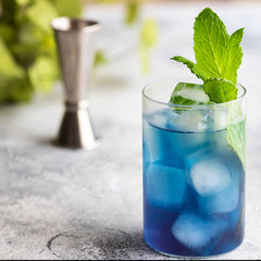 Blue lagoon, Tropical cocktail served with ice cubes decorated with mint. Refreshing alcohol drink for party at summer.