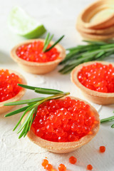Tartlets with caviar and rosemary on white table, space for text