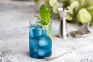 Blue lagoon, Tropical cocktail served with ice cubes decorated with mint. Refreshing alcohol drink for party at summer.