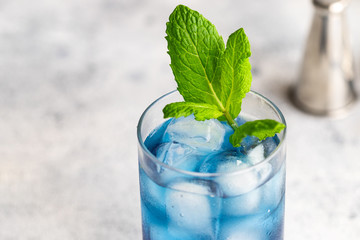 Blue lagoon, Tropical cocktail served with ice cubes decorated with mint. Refreshing alcohol drink for party at summer.
