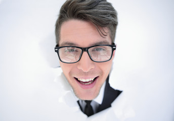 young businessman breaking through a white paper wall