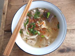 Noodle with sliced pork sausages in local white bowl and wood chopsticks on wood table in Chiang Mai,Thailand