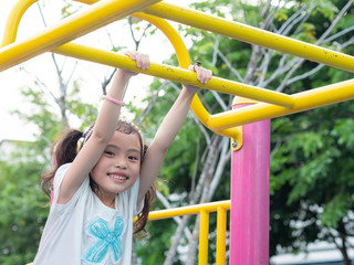 Fototapeta na wymiar Happy little cute girl 5-6 years old hanging the bar at the playground. Fun activity, brain training and learning skill, exercise