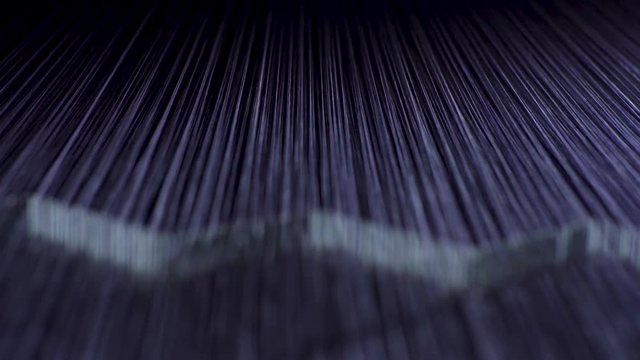 Denim cotton thread being pulled toward the camera by a machine in a textile factory.