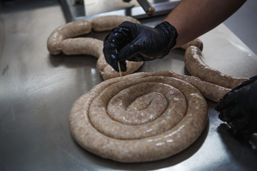 The manufacturing of meat products, a pair of gloved hands roll the mince into the gut. Meat sausages kupata twisted and beautifully stacked.