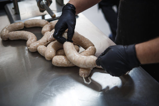 The manufacturing of meat products, a pair of gloved hands roll the mince into the gut. Meat sausages kupata twisted and beautifully stacked.