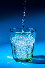 Close up pouring purified fresh drink water from the bottle on table