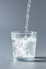 Close up pouring purified fresh drink water from the bottle on table