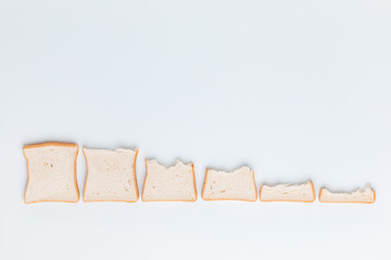 Descending line of slices of bread on a white paper background