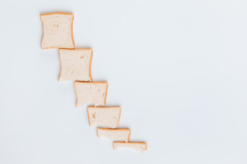 A line of slices of bread which are getting smaller and smaller, on a white background, shot from...