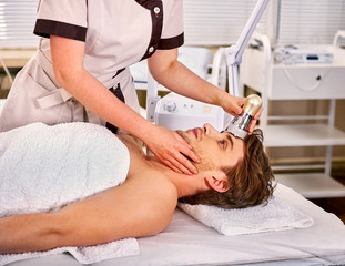 Ultrasound therapy for male skin tightening in beauty spa salon. Beautician does procedure by electric device for man in day spa .