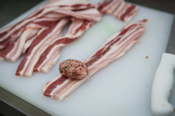 The process of preparing meat products. Gloved hands are molded from ground beef and bacon patties