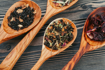 Black tea with herbs in wooden spoons on a wooden board