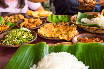 Tasty looking Indonesian food served on the table with a variety of chili sauces, rice, prawns, chicken and omlette.