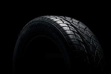 Brand new modern car tyre on a black background. Studio shot